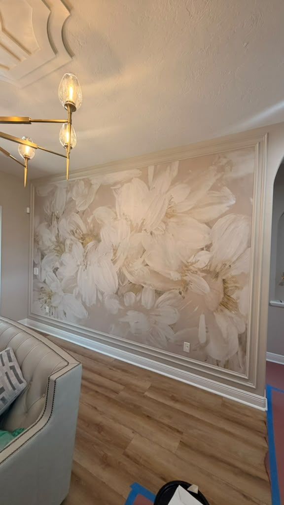 Oversized floral mural set inside decorative molding frames, creating a soft focal wall in the living area.