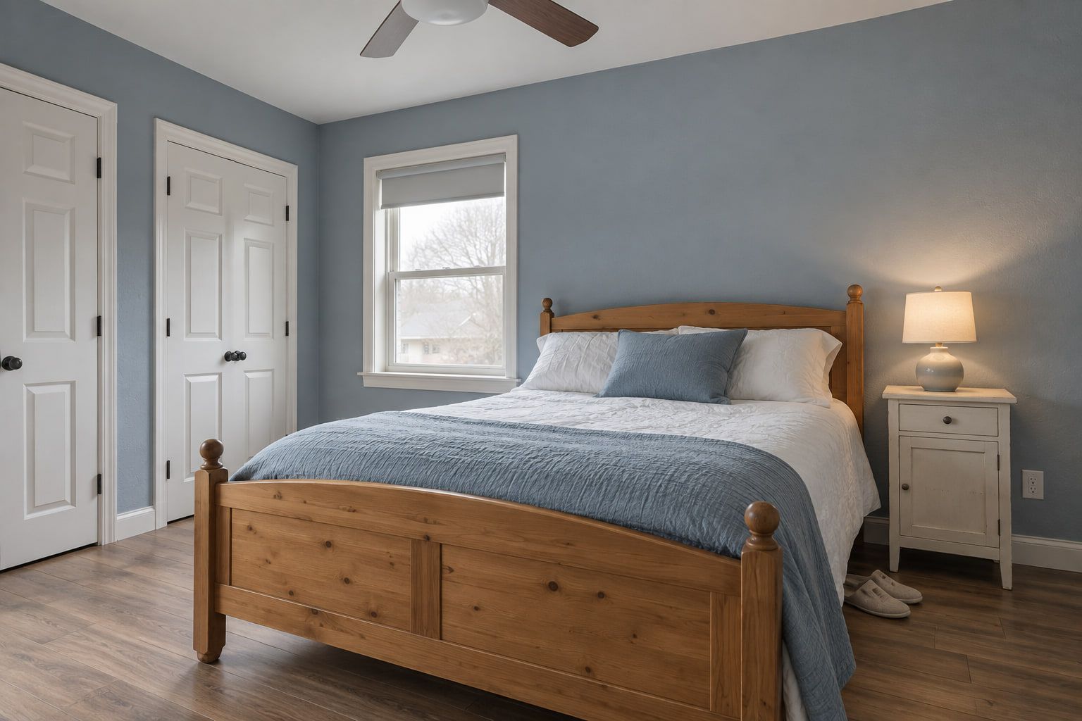 Bedroom walls painted a soft blue, with the ceiling, doors, casings, and baseboards finished in white.