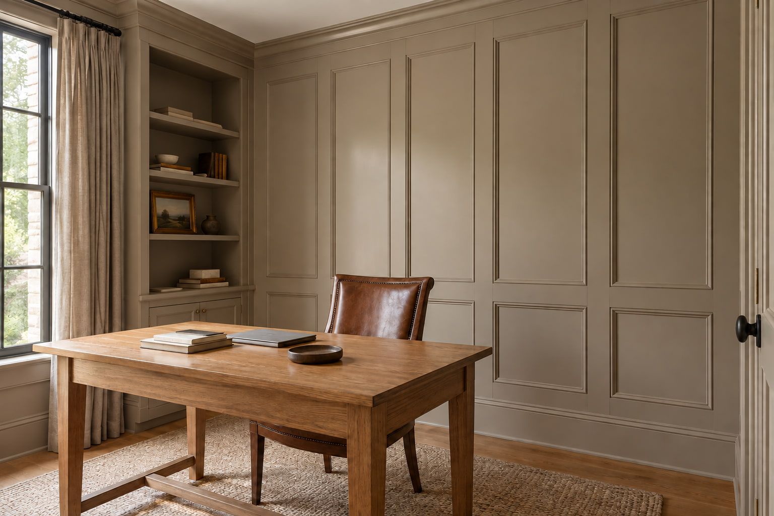 Full-wall paneling with applied molding and crown, painted in a warm taupe to match the built-in shelves.