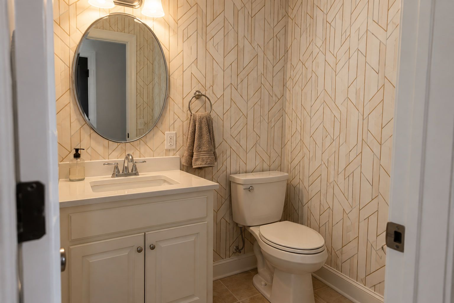 Geometric wallpaper hung on every wall of the powder room, trimmed around the mirror, vanity, outlet, and towel ring.