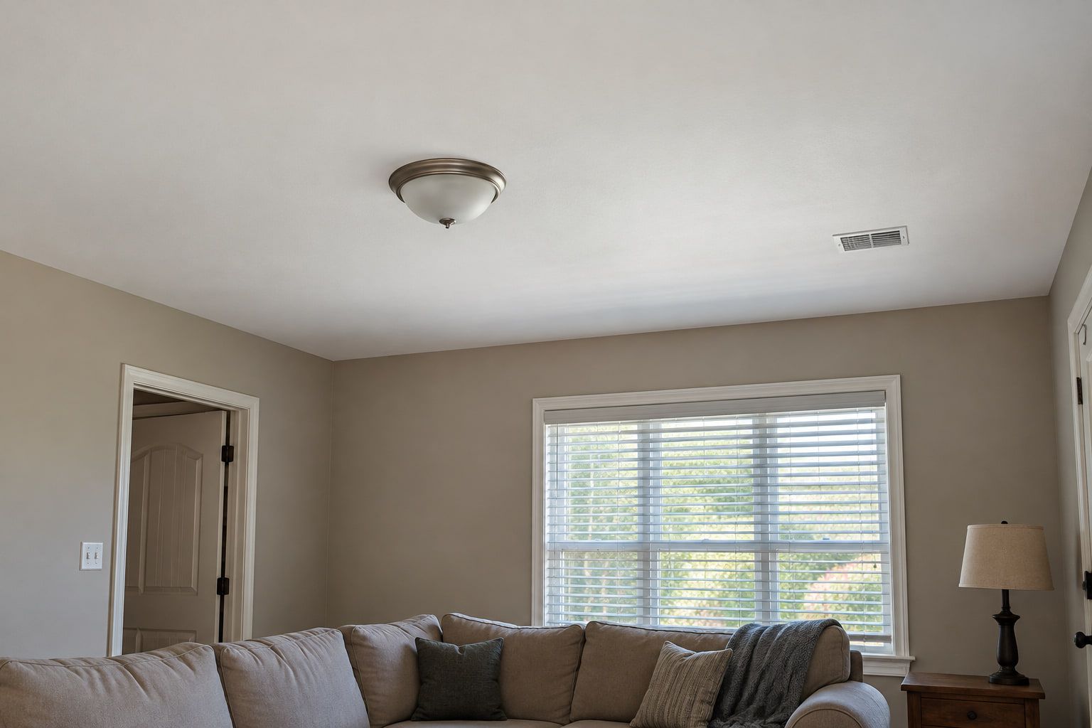 Living room ceiling painted flat white over warm gray walls, with a sharp cut line around the room.
