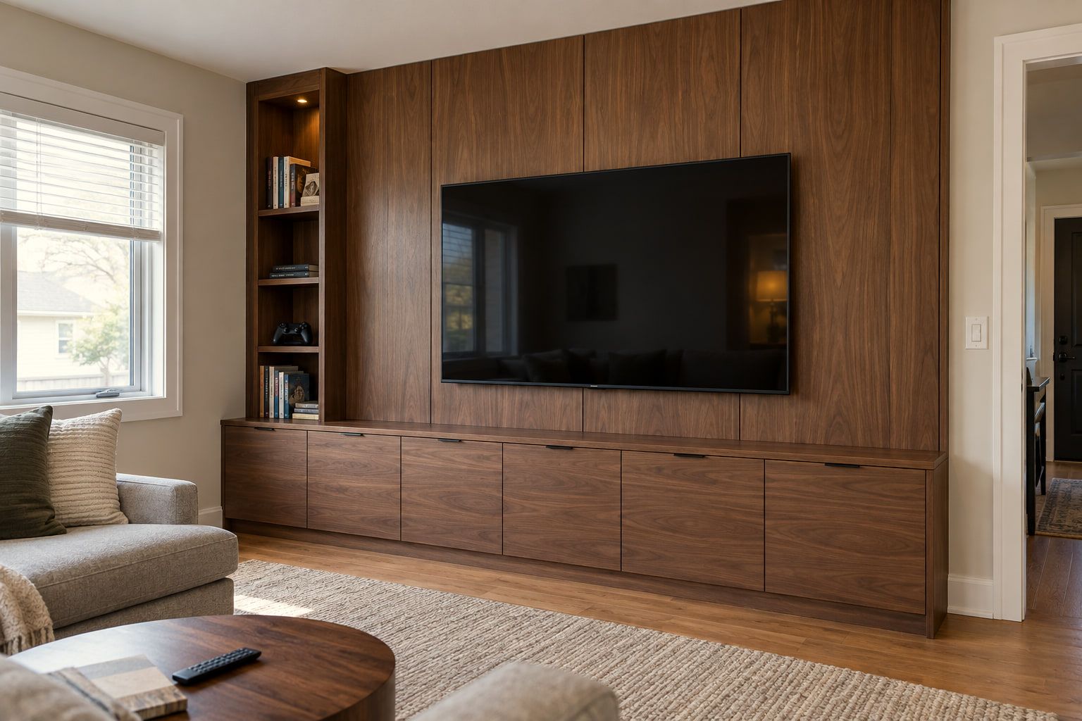 Walnut-paneled media wall with a mounted TV, a full-width base of flat-front cabinets, and an open shelving column on the left.