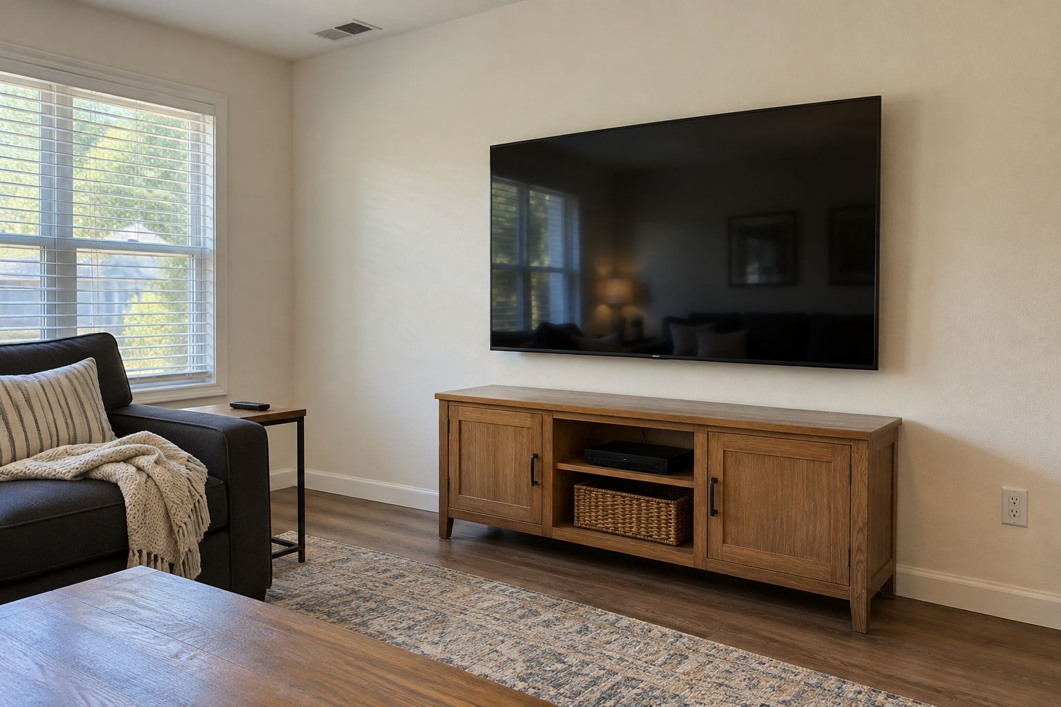 Large TV mounted flush on the living room wall with the wiring run inside the wall, above a freestanding console.